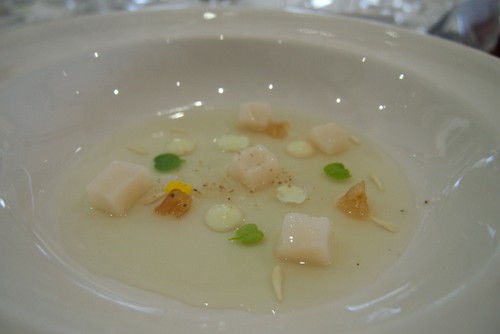 Vegetable broth with diced scallops, pine sprouts, grapes, flowers, lemons and laurel